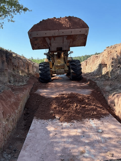 An excavator truck picking up soil on the ground
